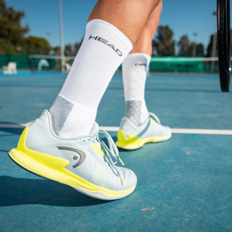 The Head Sprint Pro 3.5 Mens Tennis Shoe in Grey and Yellow on a tennis court court which are available for sale at GSM Sports