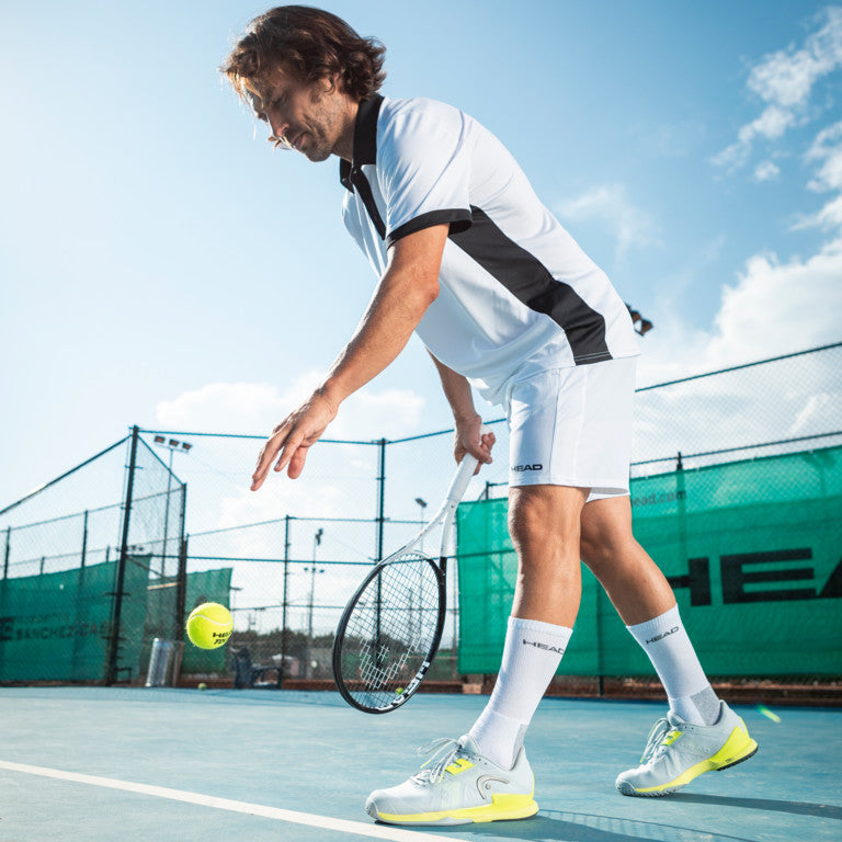 The Head Sprint Pro 3.5 Mens Tennis Shoe in Grey and Yellow on a tennis court which are available for sale at GSM Sports