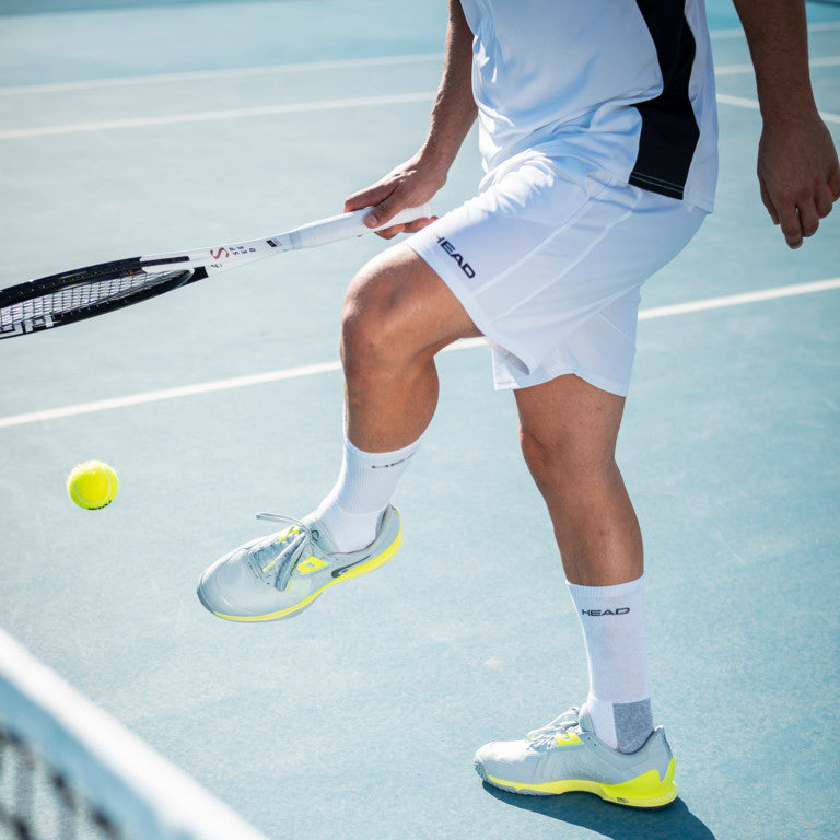 The Head Sprint Pro 3.5 Mens Tennis Shoe in Grey and Yellow on a tennis court which are available for sale at GSM Sports